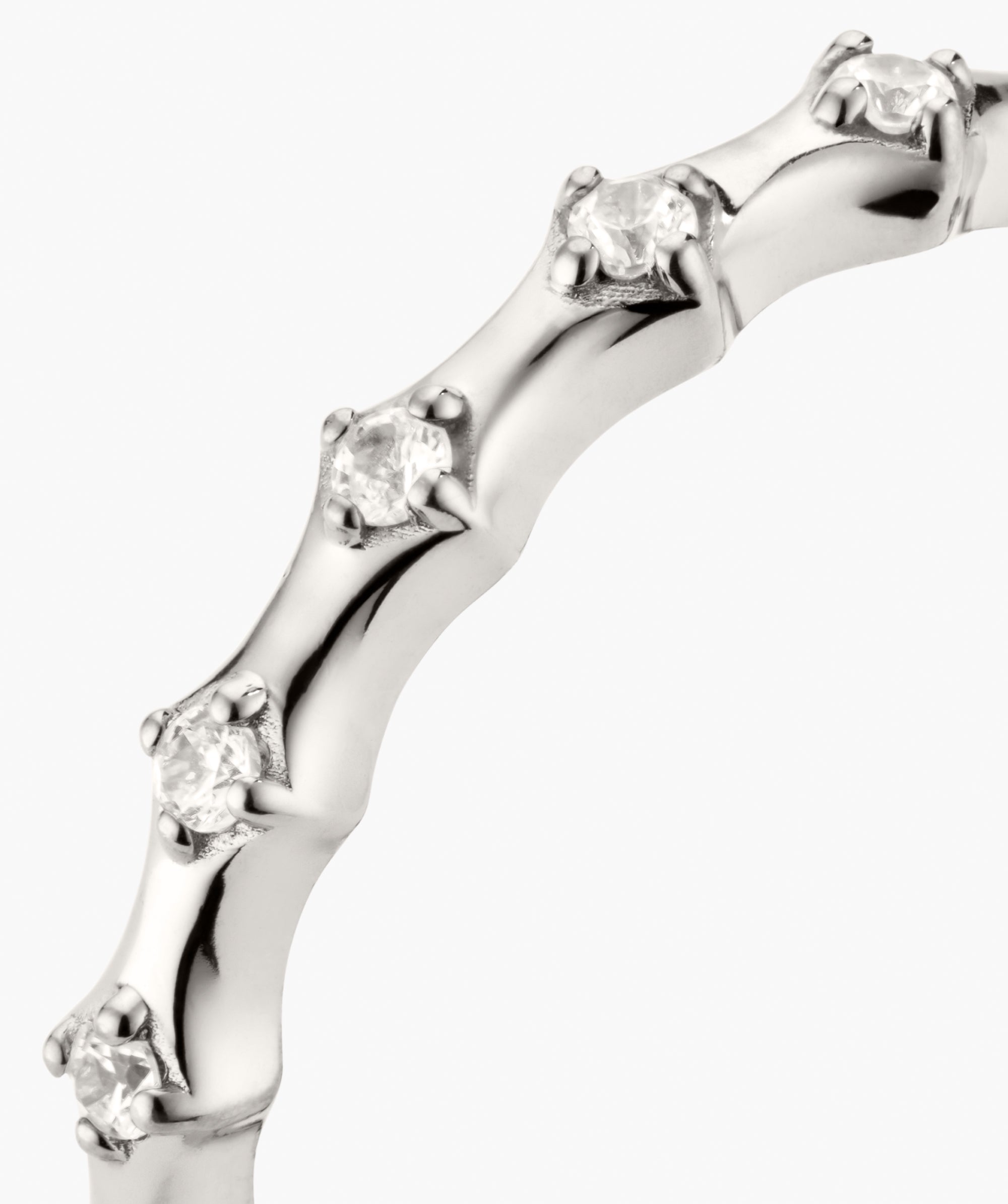 Charlotte Crest Stacker Ring, a polished white-metal band set with round brilliant-cut diamonds, showcases sculptural design and stacking versatility, enhanced by delicate sapphires.