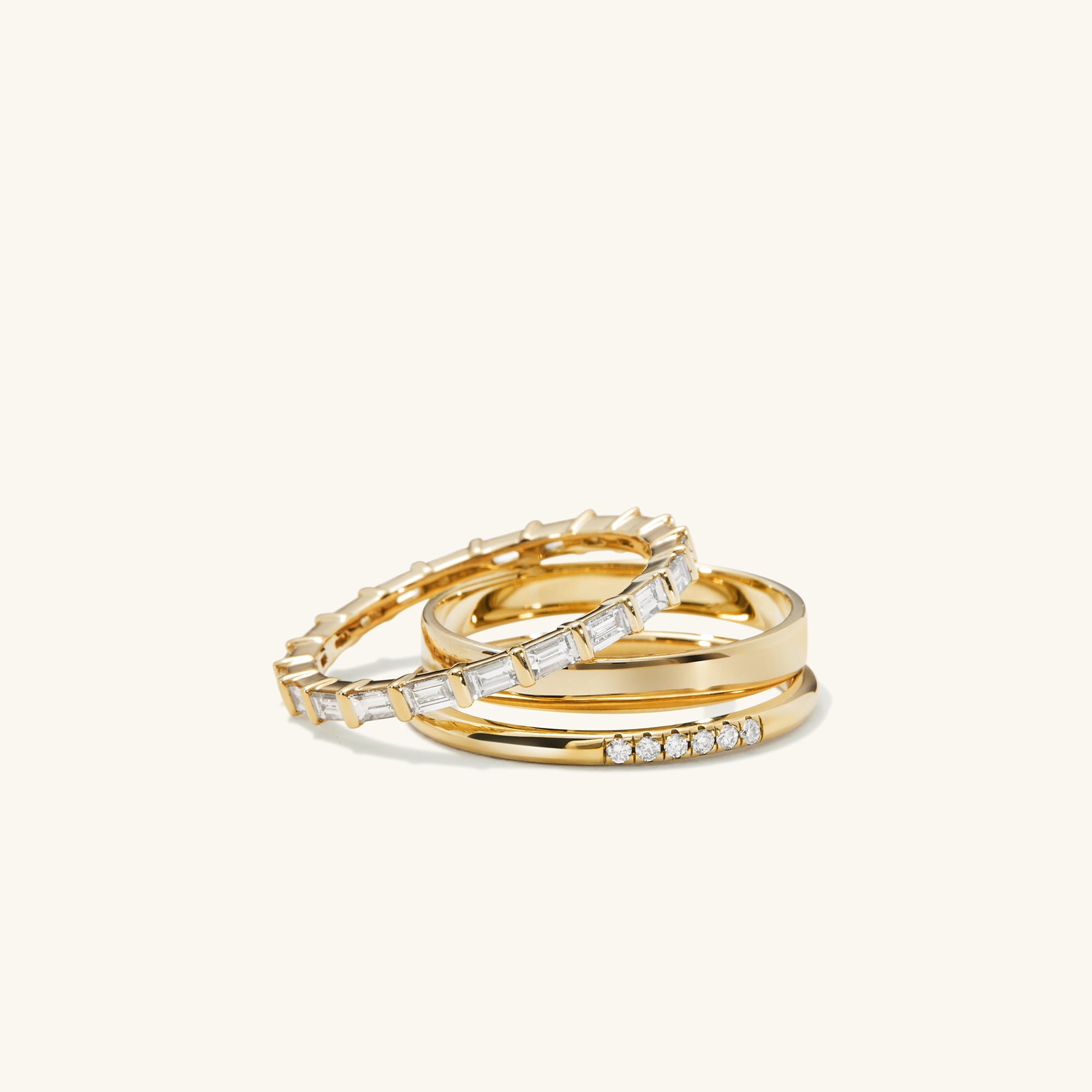 Stack of gold rings with baguette-cut diamonds in an eternity band style, featuring a 14k solid gold band and Kimberley Process-certified diamonds.