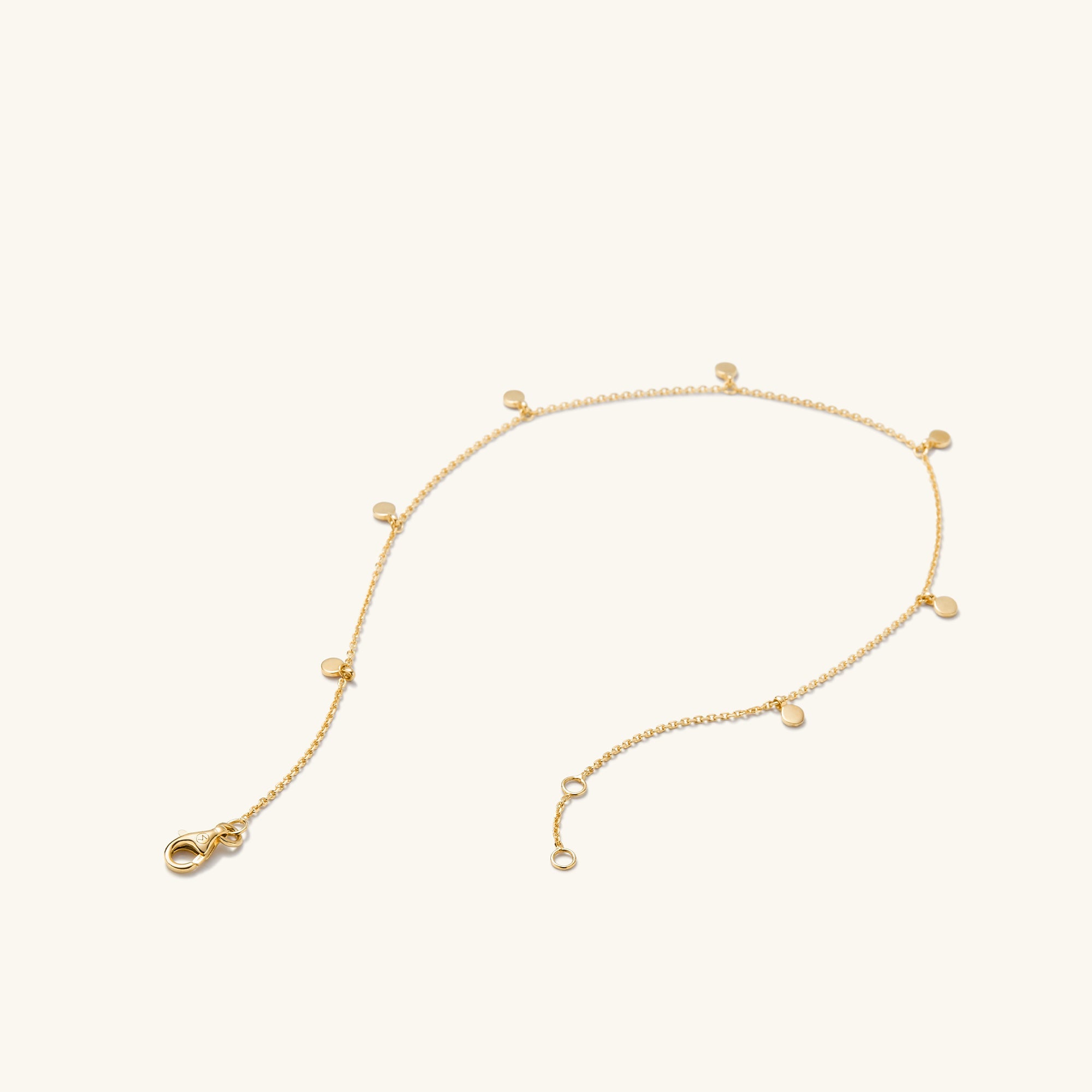Dot Chain Anklet: A close-up of a 14k solid gold chain anklet featuring small circles and dots, complete with a clasp. Handcrafted for stacking.