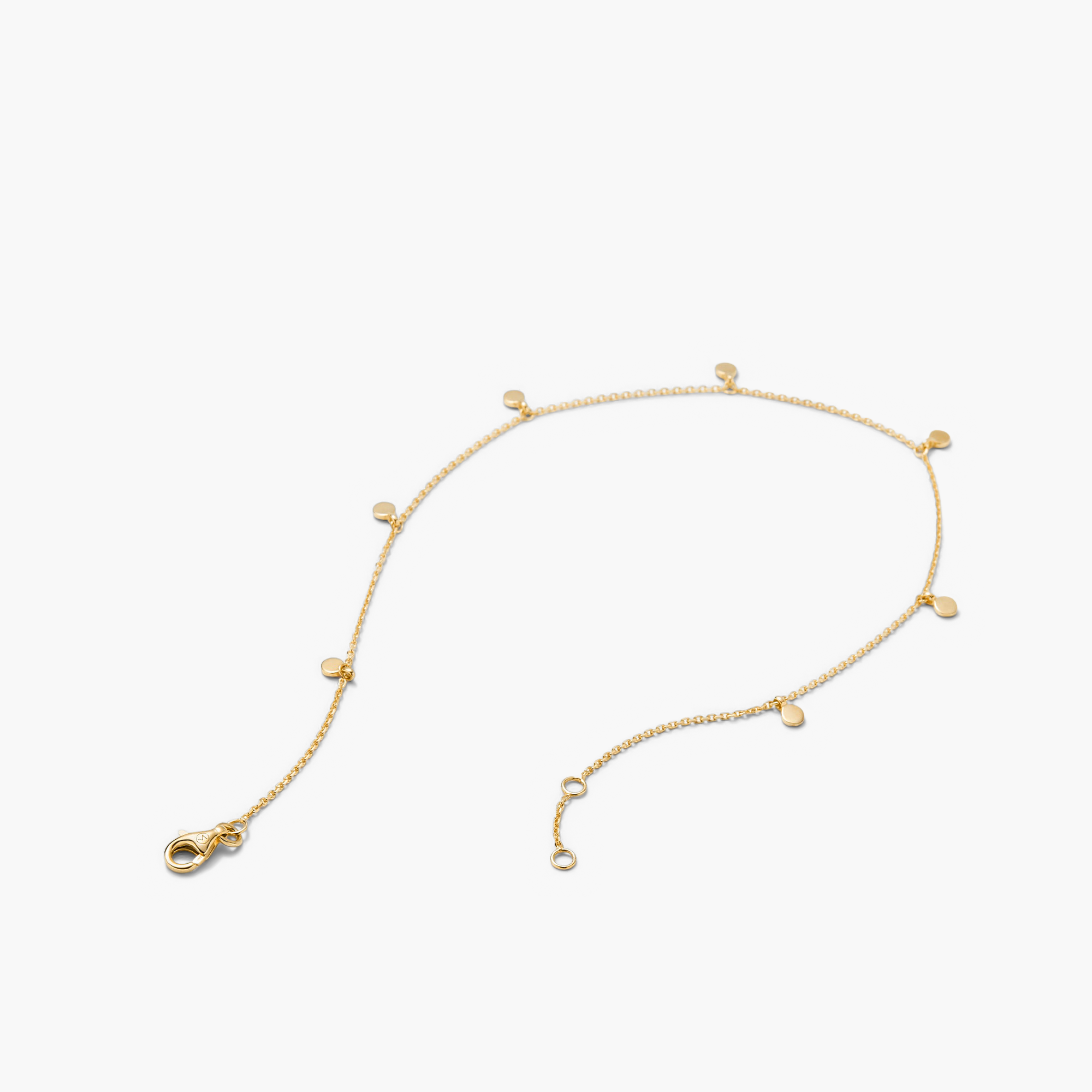 Dot Chain Anklet: A close-up of a 14k solid gold chain anklet featuring small circles and dots, complete with a clasp. Handcrafted for stacking.