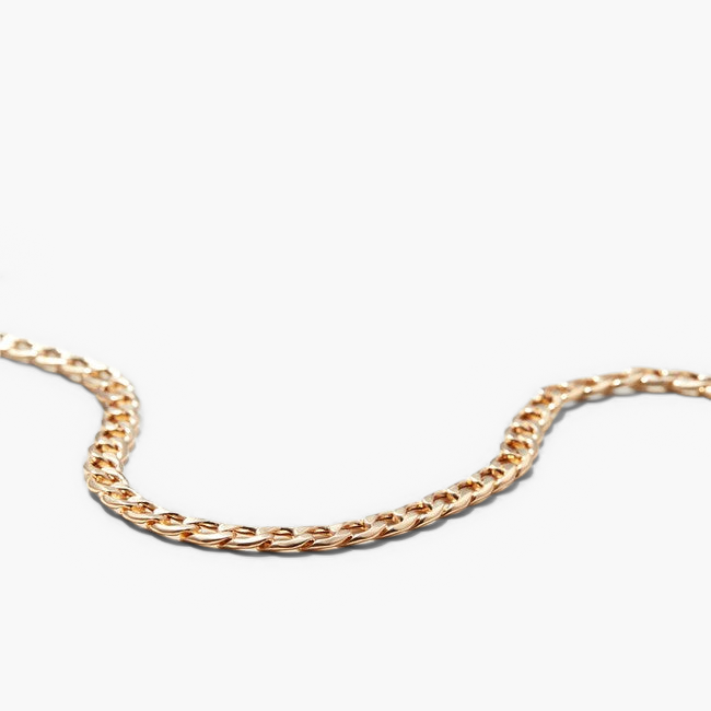 Flat Curb Chain Bracelet, a sleek gold chain on a white surface, designed for versatile wear and to elevate any look effortlessly.