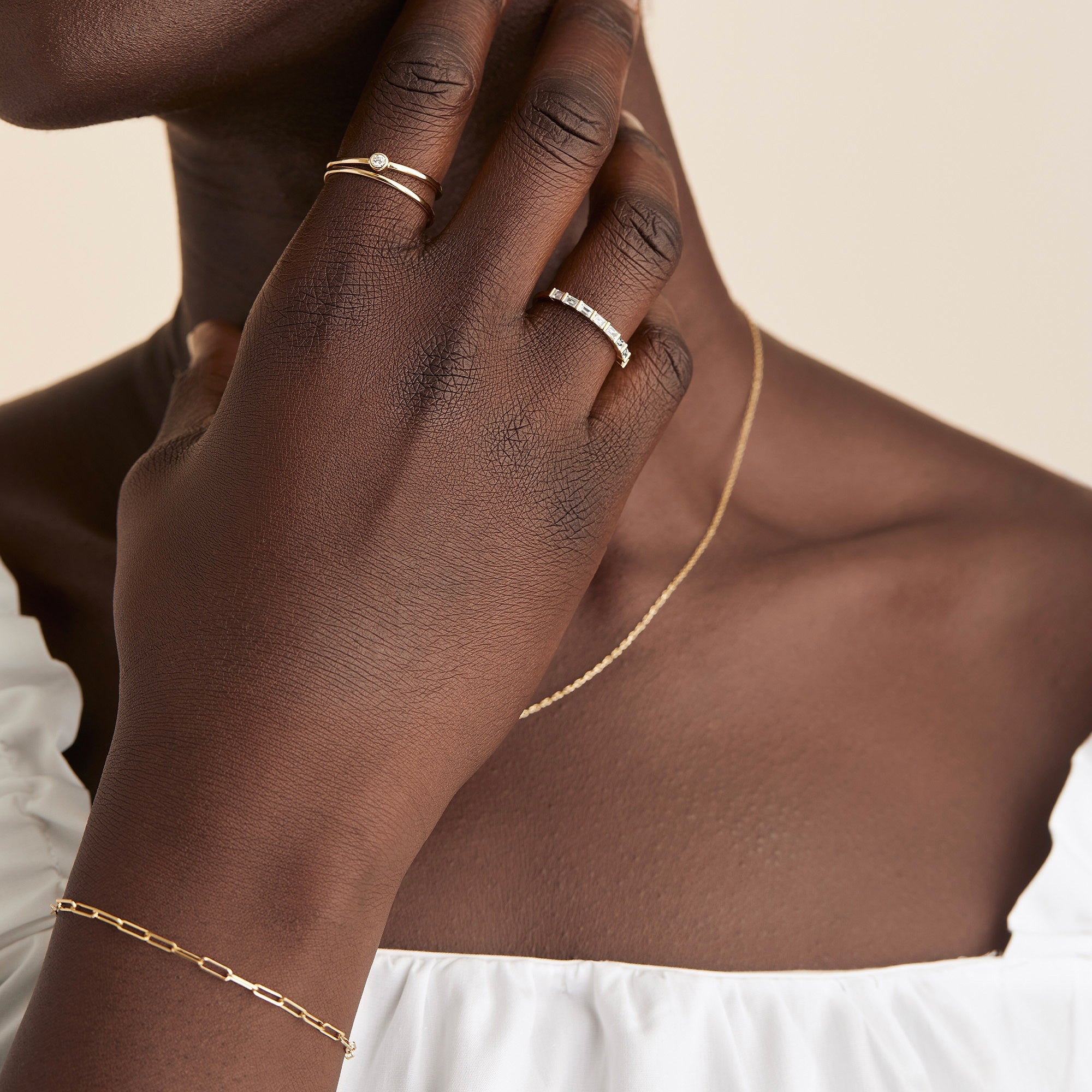 Close-up of a woman's hand wearing a Baguette Diamond Half Eternity Band, showcasing eight baguette diamonds set in a timeless gold band.