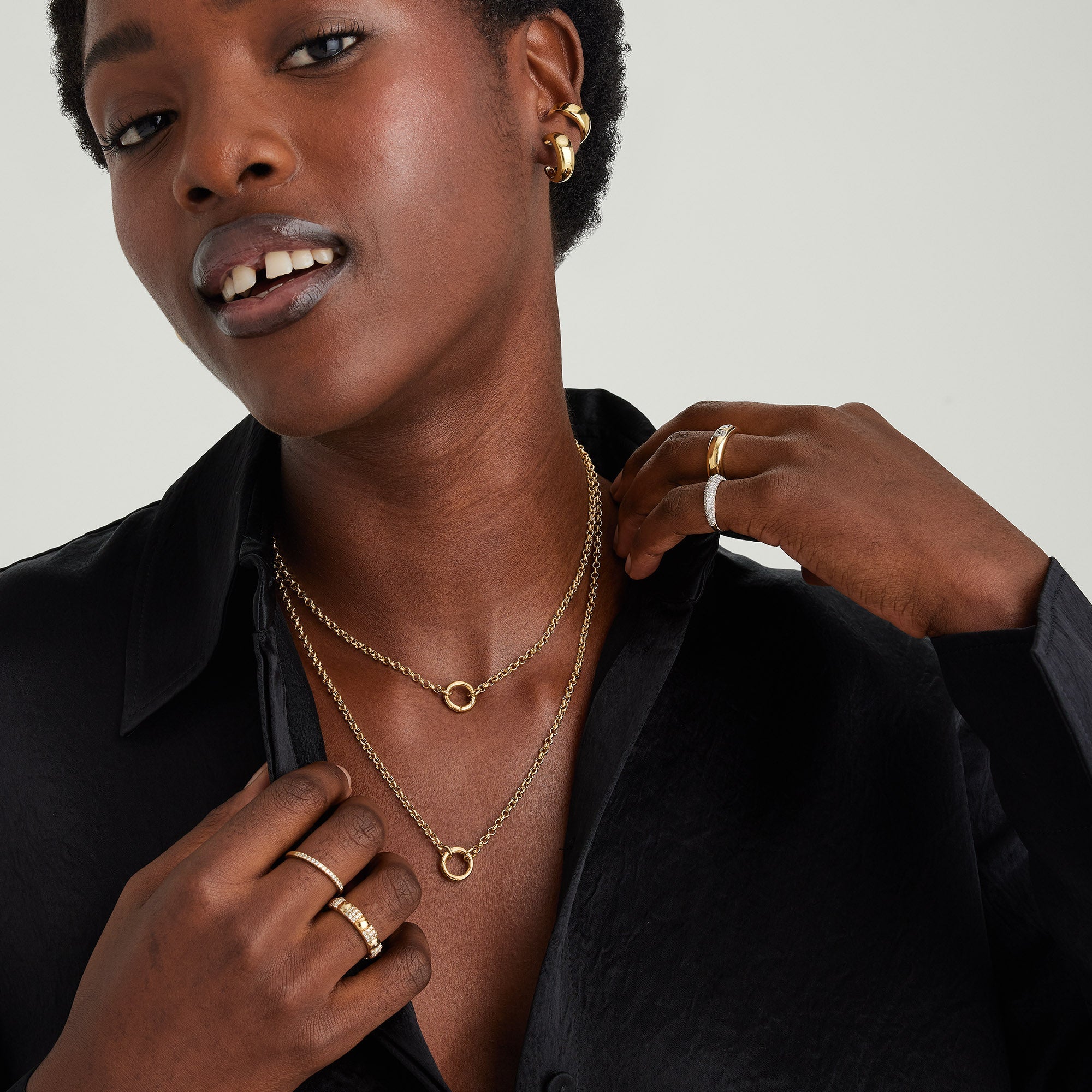 Woman wearing a Rolo Chain Charm Necklace in 14k solid gold with layered charms, shown with matching gold jewelry.