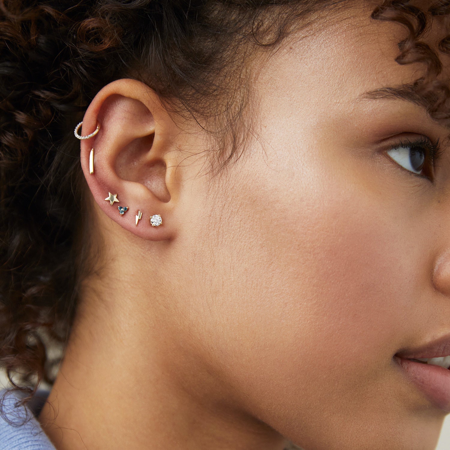 Close-up of a woman's ear wearing a Cartilage PavÃ© Diamond Mini Hoop in 14k solid gold with a hinge clasp.