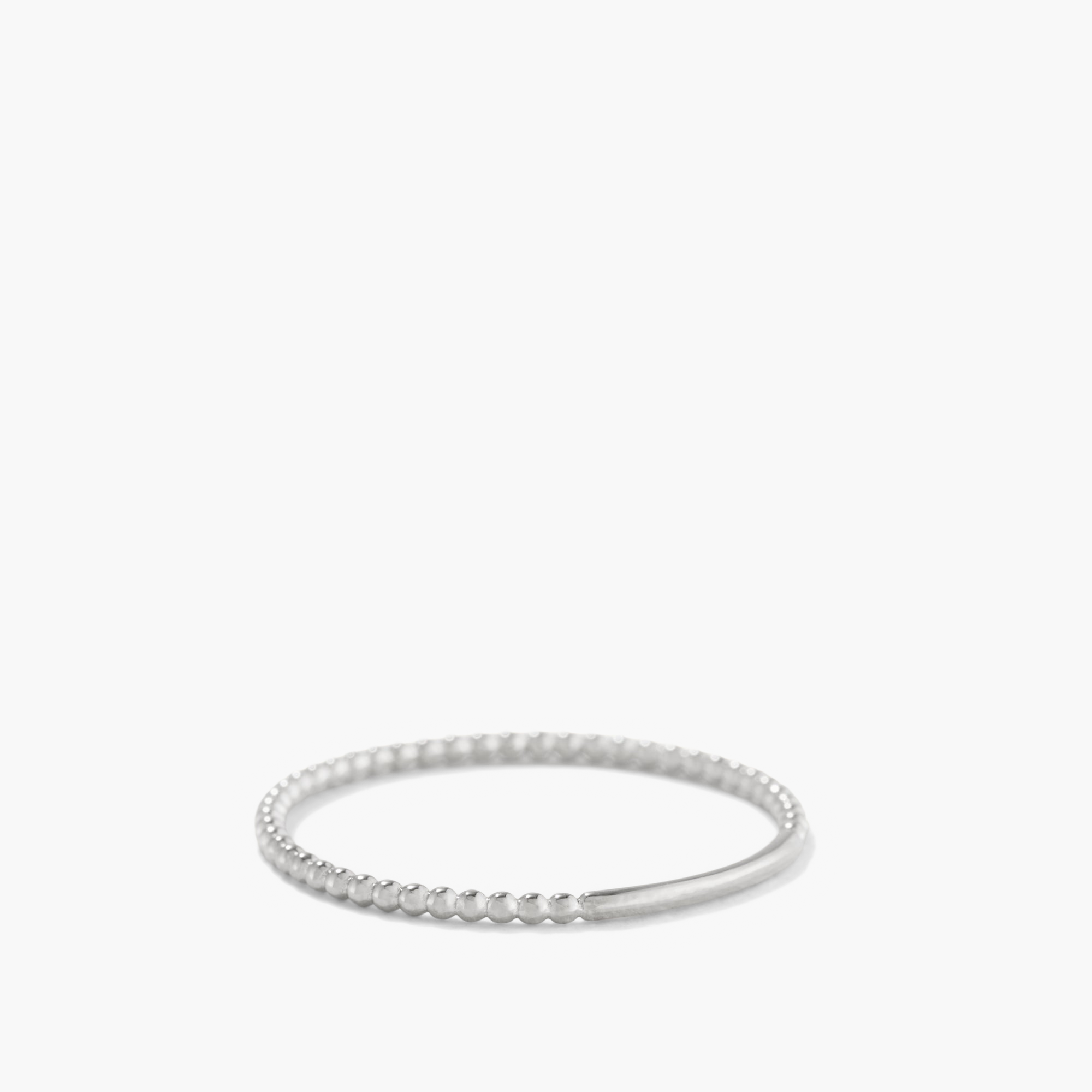 Beaded Ring: A close-up of a silver ring with a beaded band, handcrafted in 14k white gold with rhodium plating, 1.3 mm thick.