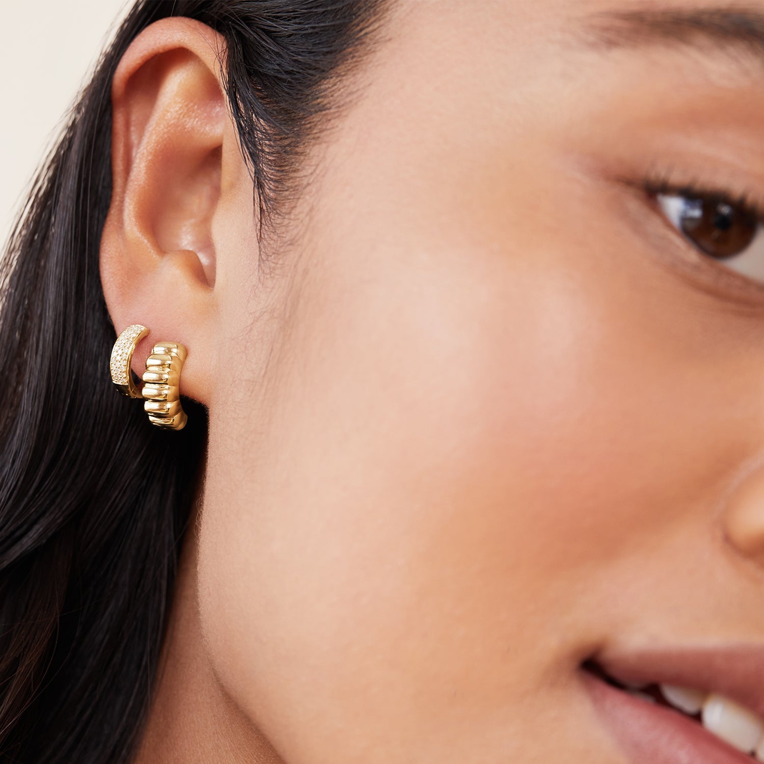 Close-up of a woman's ear wearing Charlotte Hoops, elegant gold earrings inspired by French patisserie.
