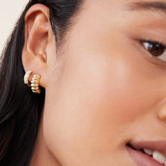 Close-up of a woman's ear wearing Charlotte Hoops, elegant gold earrings inspired by French patisserie.