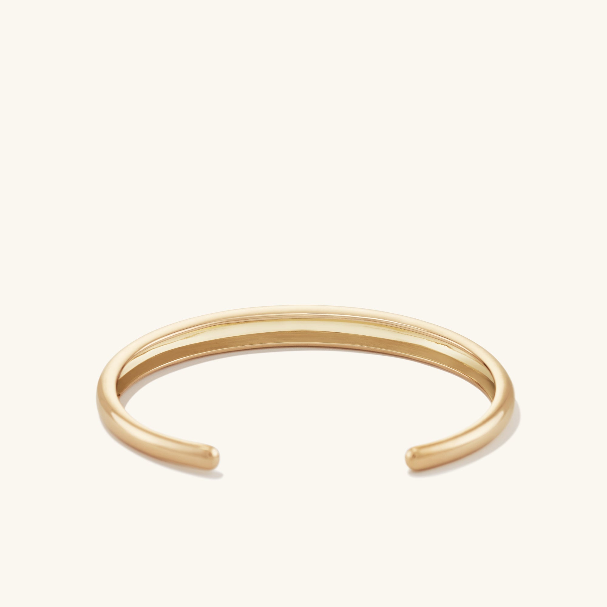 DÃ´me Cuff Bracelet: A gold bracelet with a sleek, dome-inspired design, featuring a smooth, polished surface.