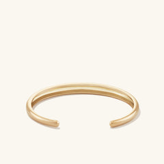DÃ´me Cuff Bracelet: A gold bracelet with a sleek, dome-inspired design, featuring a smooth, polished surface.