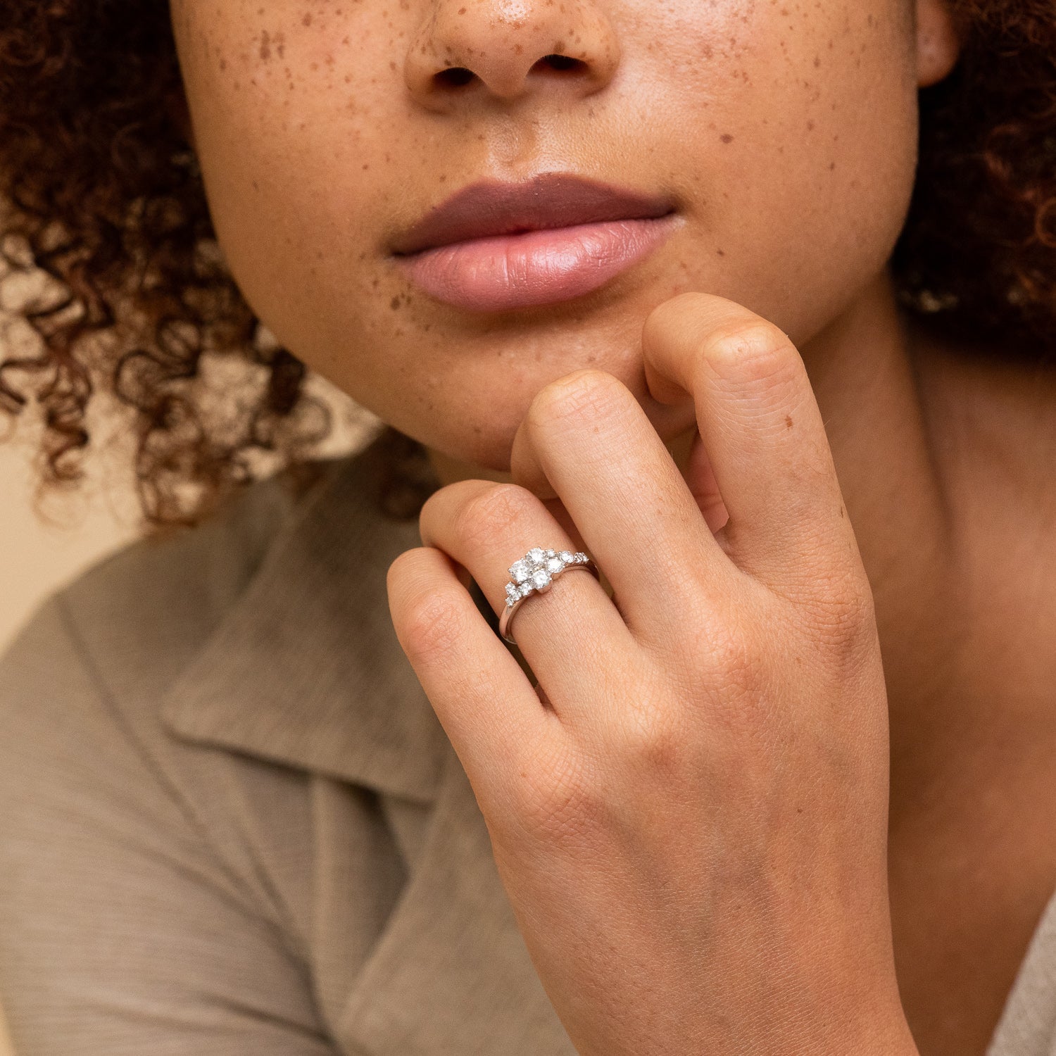 Close-up of a woman's hand showcasing the Diamonds Cluster Ring with eleven diamonds in prong settings, emphasizing its asymmetric shape and organic style.