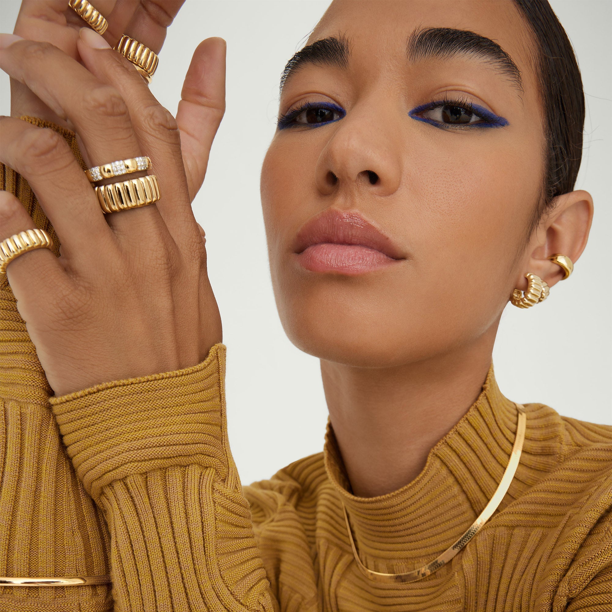 Woman wearing the Charlotte Bold Ring, a gold jewelry piece inspired by French desserts, elegantly showcased on her hand with other gold accessories.