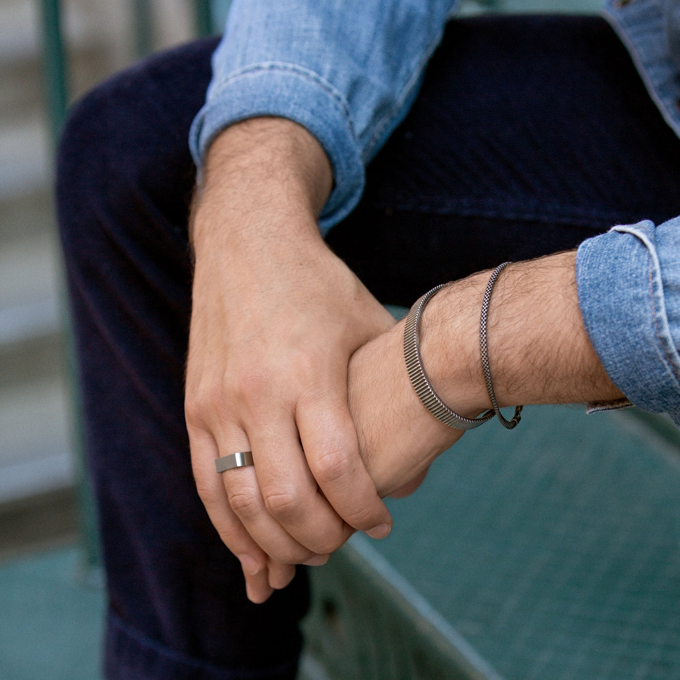 Close-up of a person's hand wearing a Slim Rectangular Signet Ring along with bracelets, highlighting the ring's bold and substantial design.
