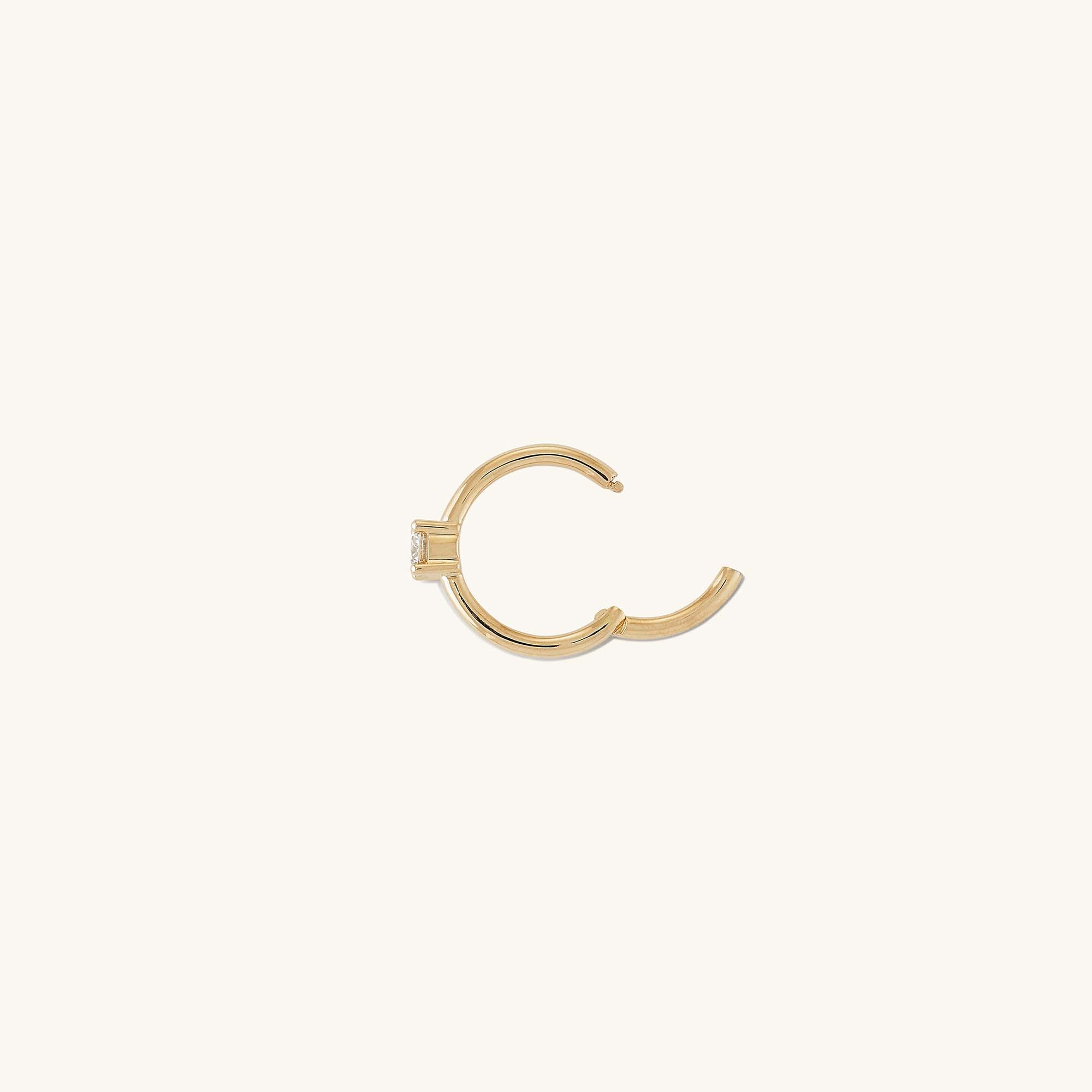 Cartilage Solo Diamond Mini Hoop: A close-up of a handcrafted 14k gold mini hoop earring with a hinge clasp, featuring a small diamond.