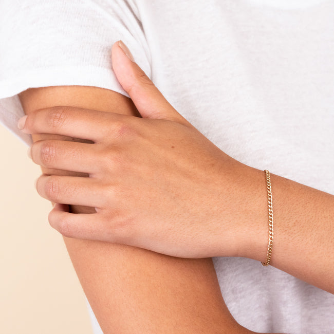Person wearing a Curb Bracelet, a handcrafted 14k solid gold chain, designed for daily wear, including work, showering, and workouts.