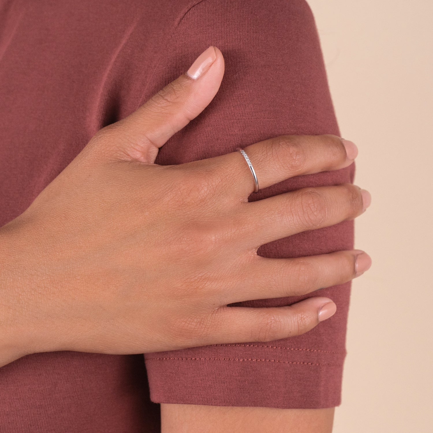 Person wearing a red shirt showcasing a 14k solid gold Diamonds Line Ring with six responsibly sourced diamonds in a prong setting for added shine.